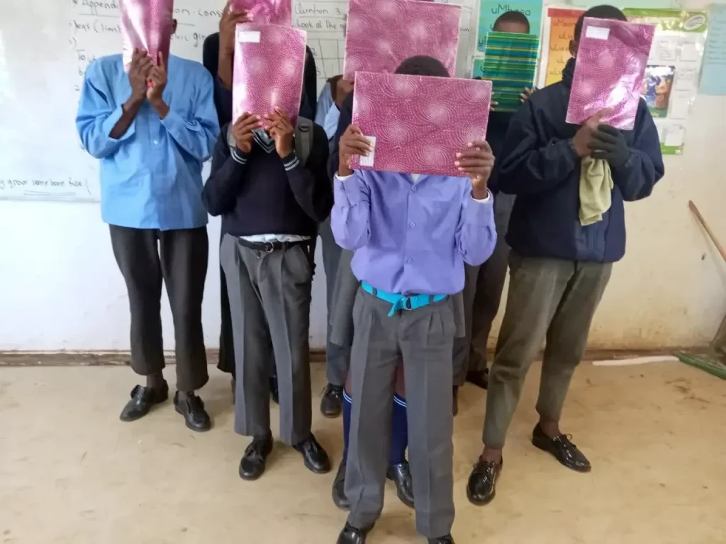 School children holding stationery donated by Sizanani