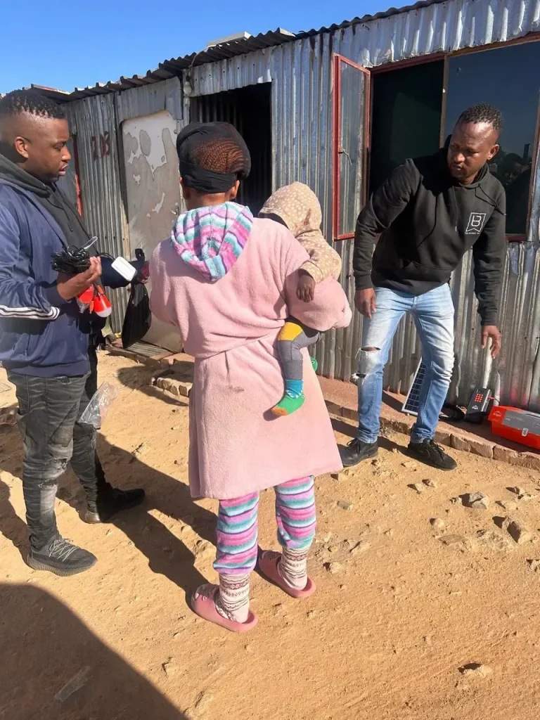 A family with the Sizanani team outside their home